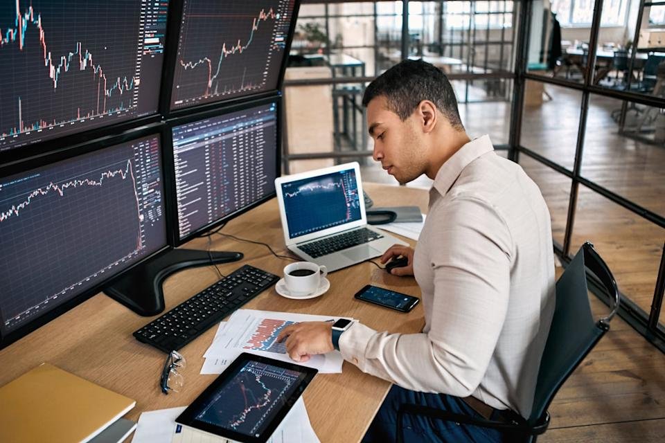 An investor looks at data on several different monitors.