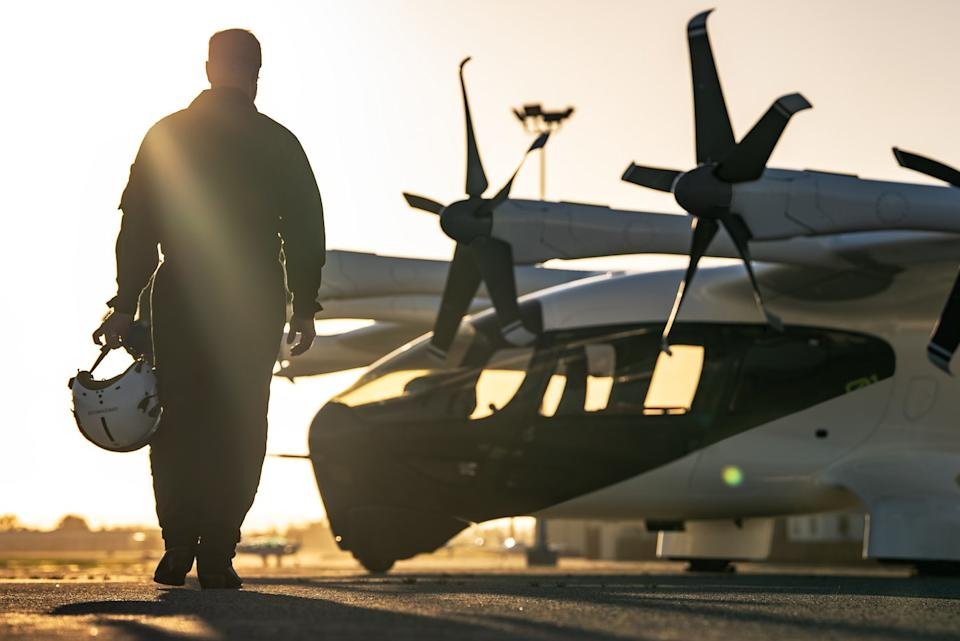 A pilot walks toward an Archer Midnight aircraft. 