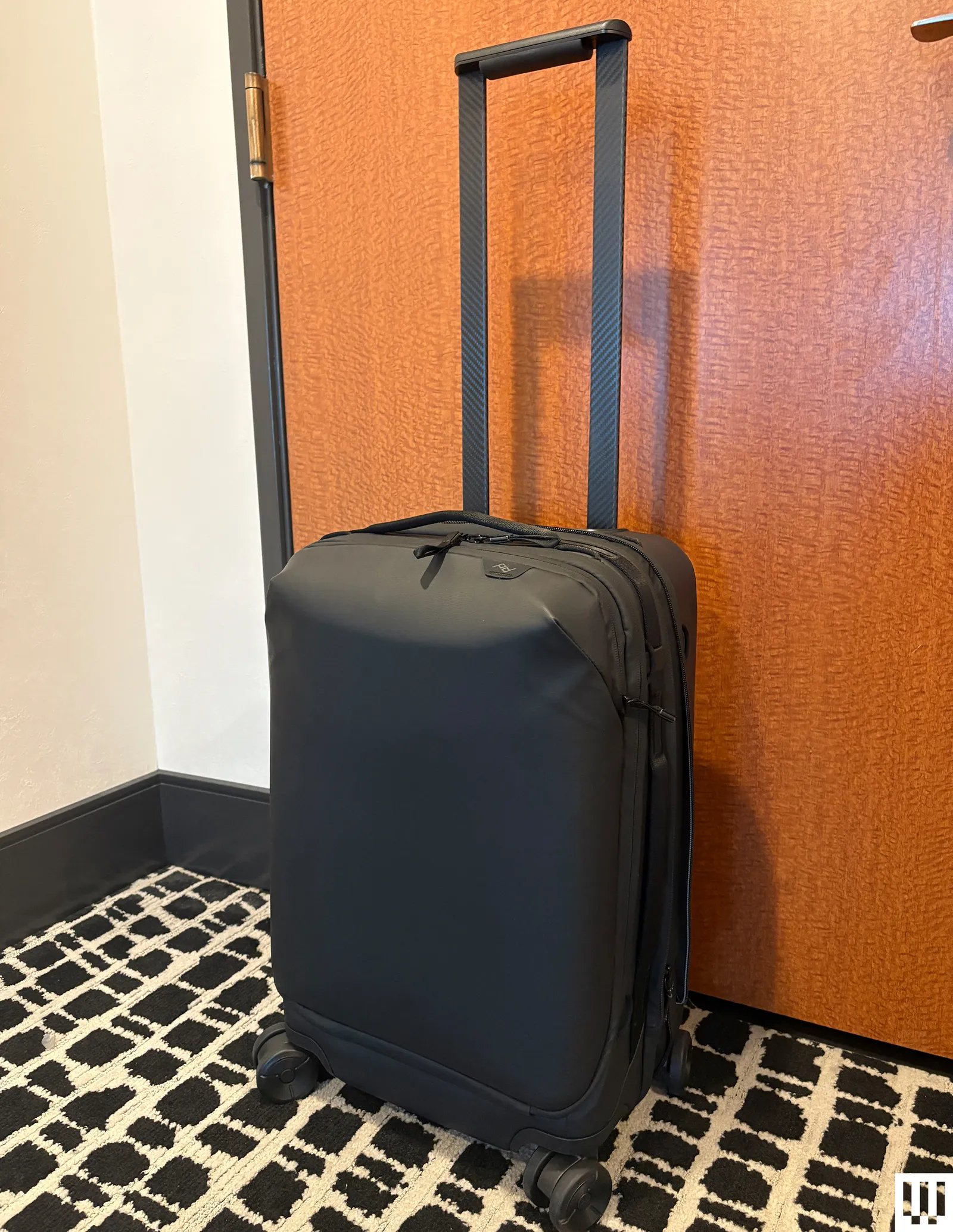 Peak Design Roller Pro black rectangular luggage with wheels and the handle extended upwards