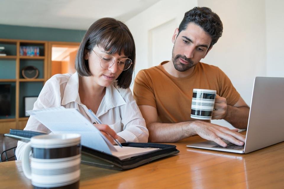 A couple using a laptop and reviewing documents.