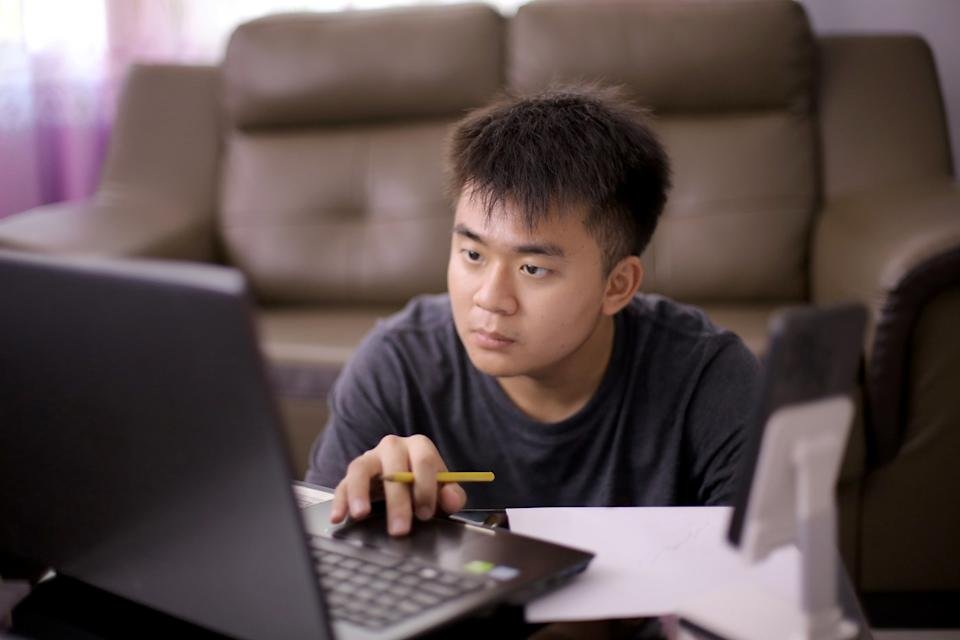 Investor sitting on floor near couch with laptop.