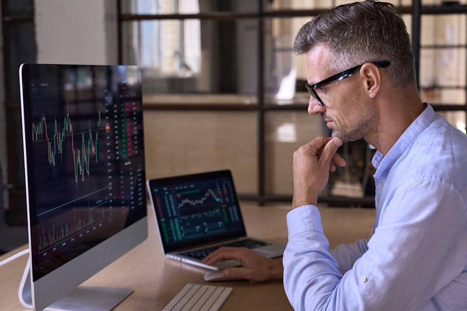 Man looking at financial charts on a screen.
